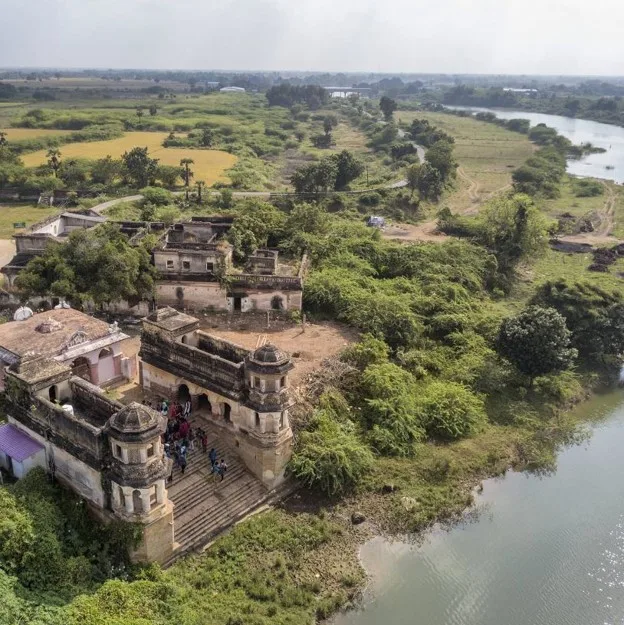 Aerial view of a sprawling historic temple complex situated along a riverbank.