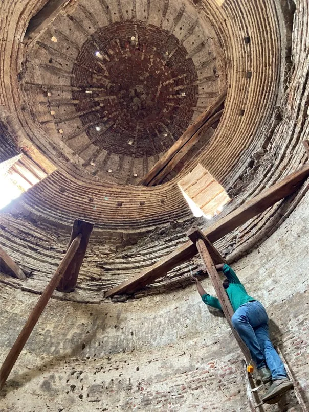 Architectural researcher conducting precision measurements inside a historic brick tower.