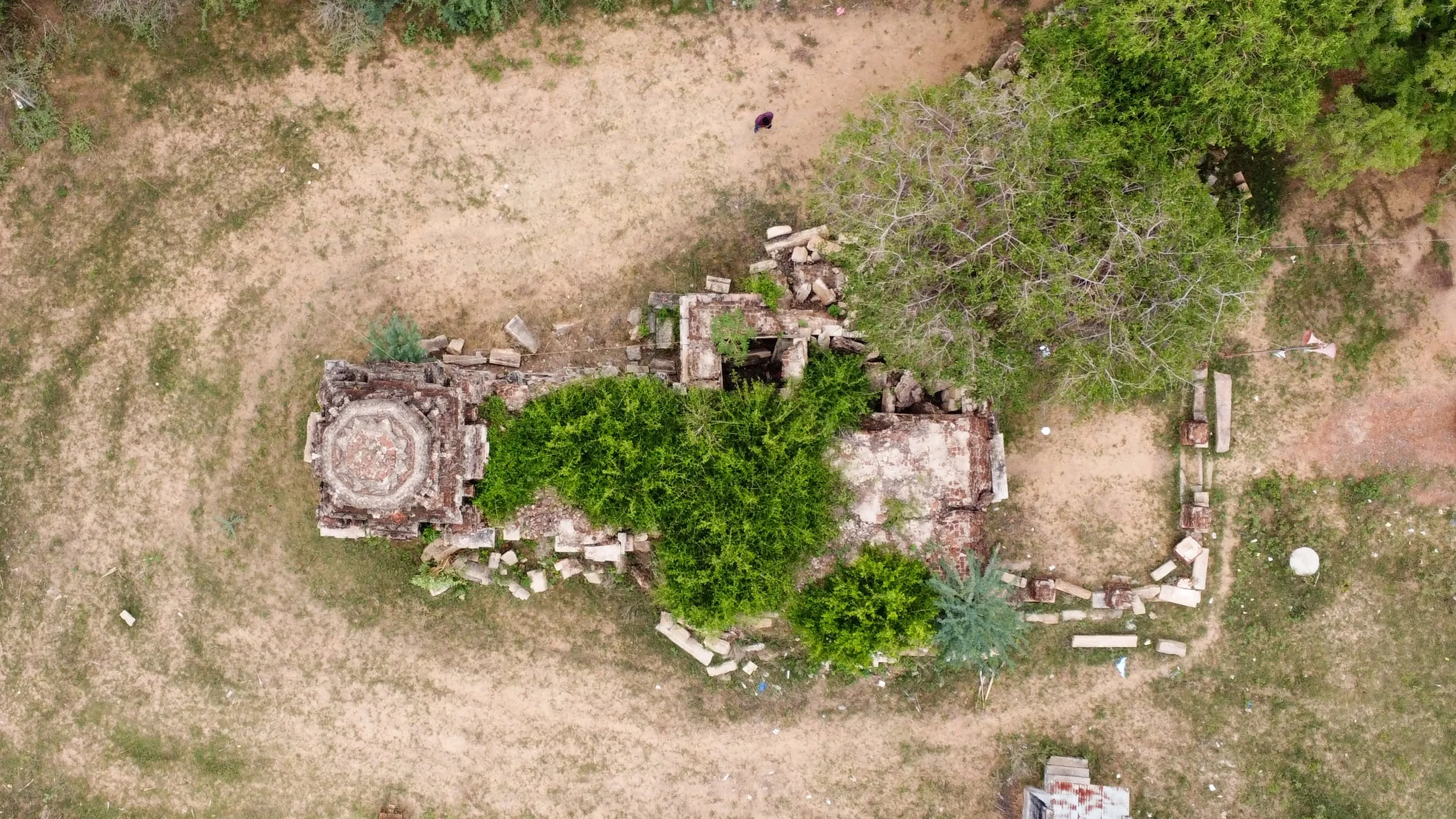 Top-down aerial drone survey showing octagonal shikhara and ruined mandapa plan with researcher.